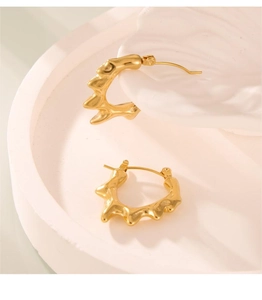 Détail de boucles d'oreilles dorées irrégulières en C avec texture de lave polie