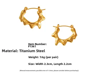 Vue détaillée des boucles d'oreilles C en acier titane avec texture lave en fini doré
