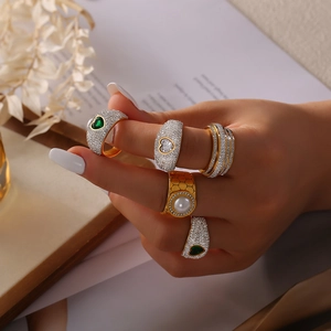 Set de anillos de acero de titanio dorado con corazón esmeralda, perlas y cristales en mano