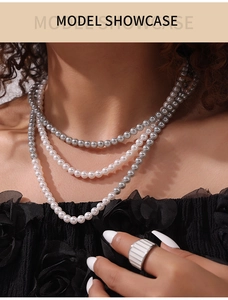 Gros plan d'un collier de perles gris et blanc à trois rangs sur un mannequin en haut noir