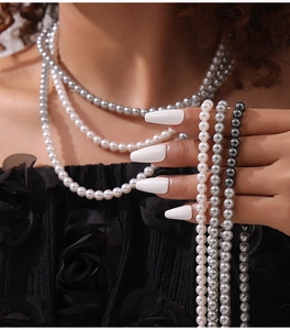 Gros plan détaillé de colliers de perles classiques en blanc, gris clair et gris anthracite