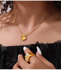 Detail van de ketting met onregelmatige hanger en brede ring met kristallen steentjes
