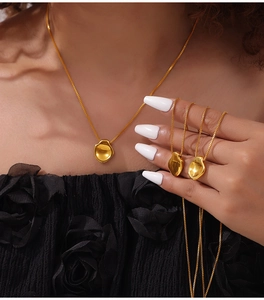 Detailopname van de onregelmatige 18K vergulde hanger ketting op zwarte getextureerde stof