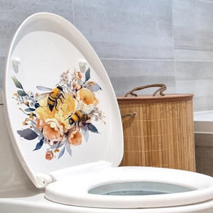 Dettaglio adesivo murale con ape e fiori su coperchio WC bianco in ambiente bagno moderno