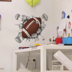 Détail d'un sticker mural 3D montrant un ballon de rugby réaliste brisant un mur blanc