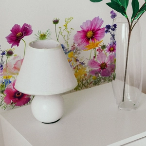 Detailed view of floral wall decals behind a white minimalist ceramic table lamp