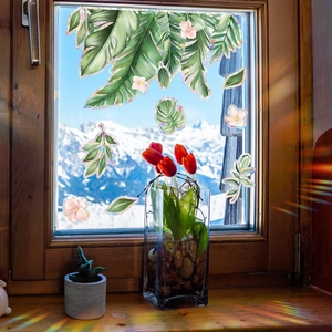 Regenbogen-Fensterfolie mit tropischen Blättern und Blumen auf einer Glasscheibe