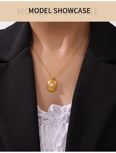 Détail d'un collier en titane plaqué or 18k avec pendentif spirale et perle blanche