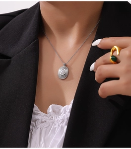 Détail du collier pendentif ovale argenté avec texture radiale et incrustation de perle