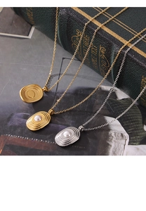 Gros plan de colliers en titane plaqué or 18k avec perles nacrées sur fond de livre ancien