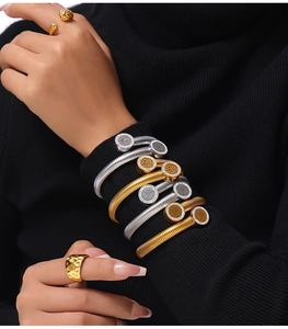 Détail de bracelets à ressort multicouches en or et argent avec pavé de diamants sur maille