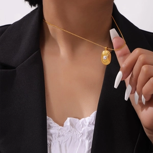 Collier en acier titane plaqué or 18 carats avec pendentif ondulé et perle sur mannequin