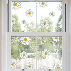 Detailed view of white daisy window stickers on glass with a blurry garden background
