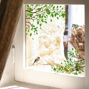Détail de branches de feuilles vertes et d'autocollants statiques d'oiseaux sur verre