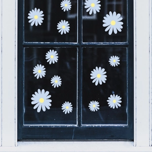 Close-up of daisy floral window decals on glass with purple petals and yellow center