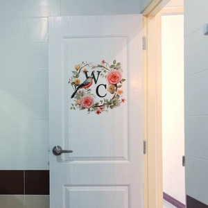 Sticker mural couronne de fleurs avec oiseau et signe WC sur une porte blanche