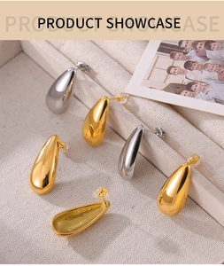 Detailed view of polished teardrop stud earrings in gold and silver finish on canvas tray