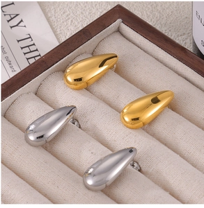 Macro shot of polished gold and silver teardrop earrings on a linen jewelry tray