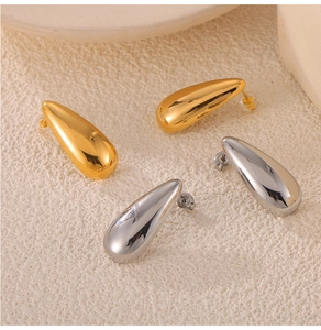 Macro shot of minimalist teardrop stud earrings in polished gold and silver steel finish