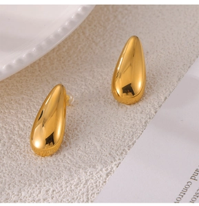 Macro shot of gold teardrop earrings with high-polish finish on a minimalist background