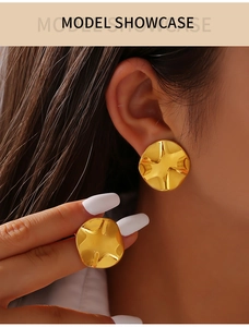 Macro view of gold-plated hoop earrings with irregular wave texture on a model