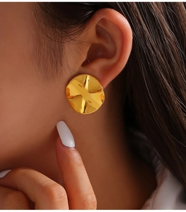 Close-up of elegant gold 18k plated titanium steel earrings with wavy textured surface