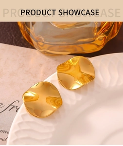 Detailed view of irregular square gold earrings with wavy texture on white plate