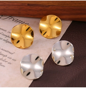 Detail view of gold and silver irregular concave round stud earrings on vintage background