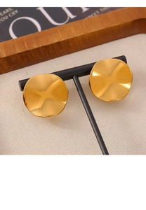 Macro detail of irregular wavy gold earrings on a display stand with elegant warm lighting