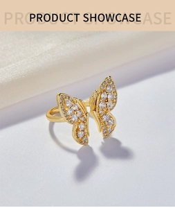 Gros plan sur une bague papillon plaquée or avec pavé de zircons sur fond de tissu blanc