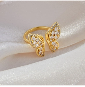 Vue macro d'une bague papillon dorée avec zircons blancs sur tissu en soie