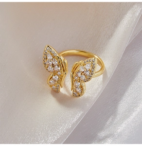 Gros plan d'une bague papillon dorée avec pavage de zircons sur un fond en soie élégant