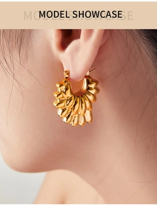 Gros plan sur un mannequin portant une boucle d'oreille créole dorée à texture froissée
