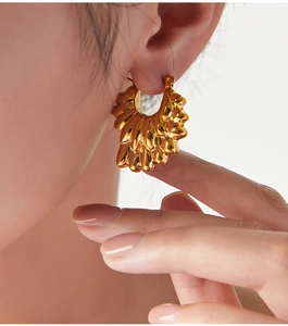 Gros plan de boucles d'oreilles pétales dorées avec relief en forme de coquillage