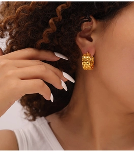 Detail of C-shaped titanium steel earrings with braided chain texture on female ear
