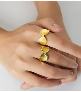 Dettaglio del set di anelli placcati oro con pietre verdi e pavé di zirconi bianchi