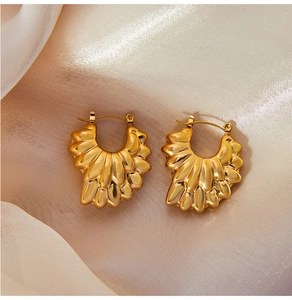 Détail de boucles d'oreilles dorées 18 carats en forme d'éventail sur soie champagne