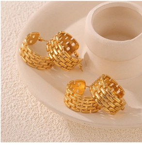 Close-up of golden C-shaped chain-link earrings on a white minimalist display tray