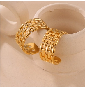 Detail of gold-plated C-shaped chain link earrings displayed on a ceramic vessel