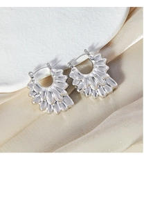 Détail de boucles d'oreilles pétales argentées sur soie et plateau blanc texturé