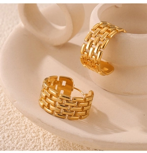 Detail of gold C-shaped chain link earrings on a ceramic dish with textured surface
