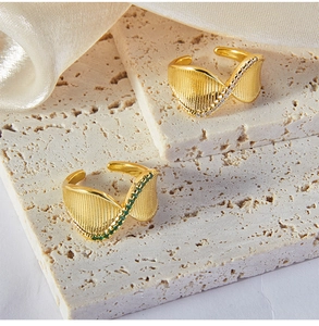 Dettaglio macro di anelli placcati in oro con pietre di smeraldo su base in pietra
