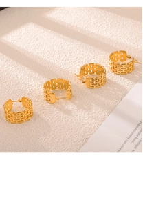 Detail of four golden C-shaped woven mesh hoop earrings with intricate hollow design