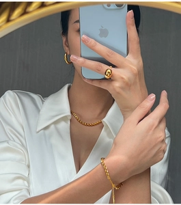 Detail view of gold-plated stainless steel jewelry set with teardrop ring and chunky chains