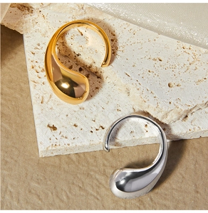 Macro detail of tear-drop minimalist rings in polished gold and silver on stone