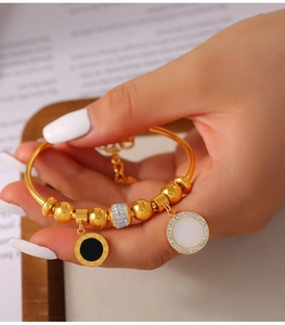Détail du bracelet en acier titane doré avec pendentifs chiffres romains et zircons