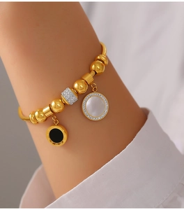 Vue détaillée du bracelet doré avec charms nacre blanche et disque romain noir en acier