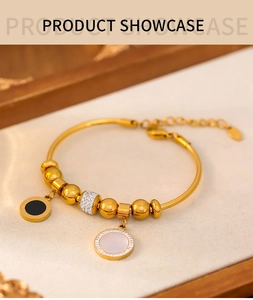 Détail du bracelet à billes dorées avec pendentifs en émail noir, nacre blanche et strass