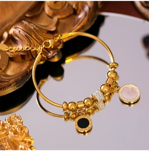Détail d'un bracelet en titane doré avec charmes à chiffres romains et cristaux