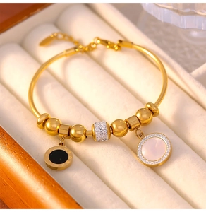 Détail du bracelet perlé doré avec breloque en cristal et pendentif en nacre
